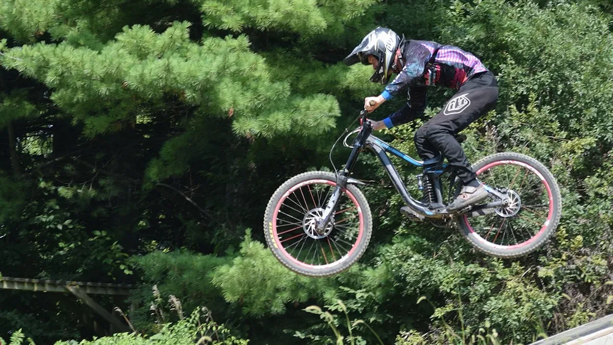 Rowerzysta w kasku w locie nad hopką na trasie bike parku, hopy rowerowe