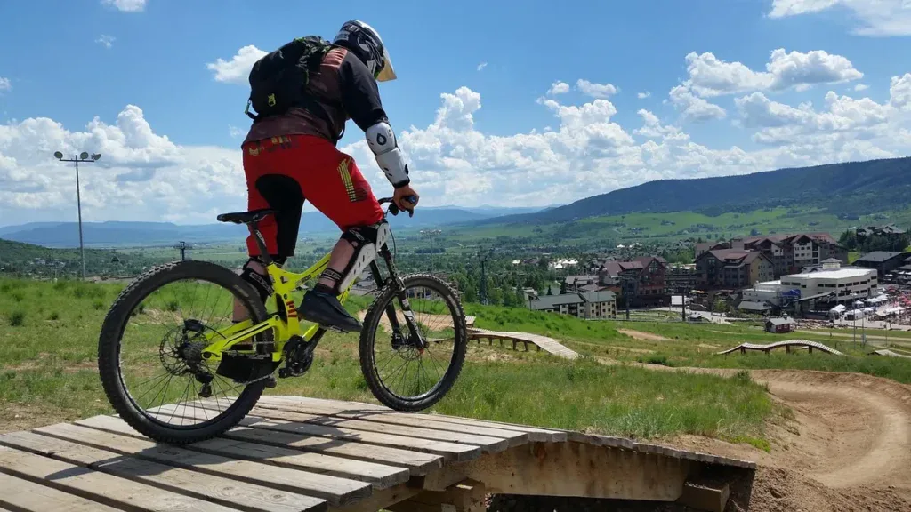 Łatwa trasa zjazdowa w bike parku: rowerzysta w kasku i ochraniaczach na niskim drewnianym podeście