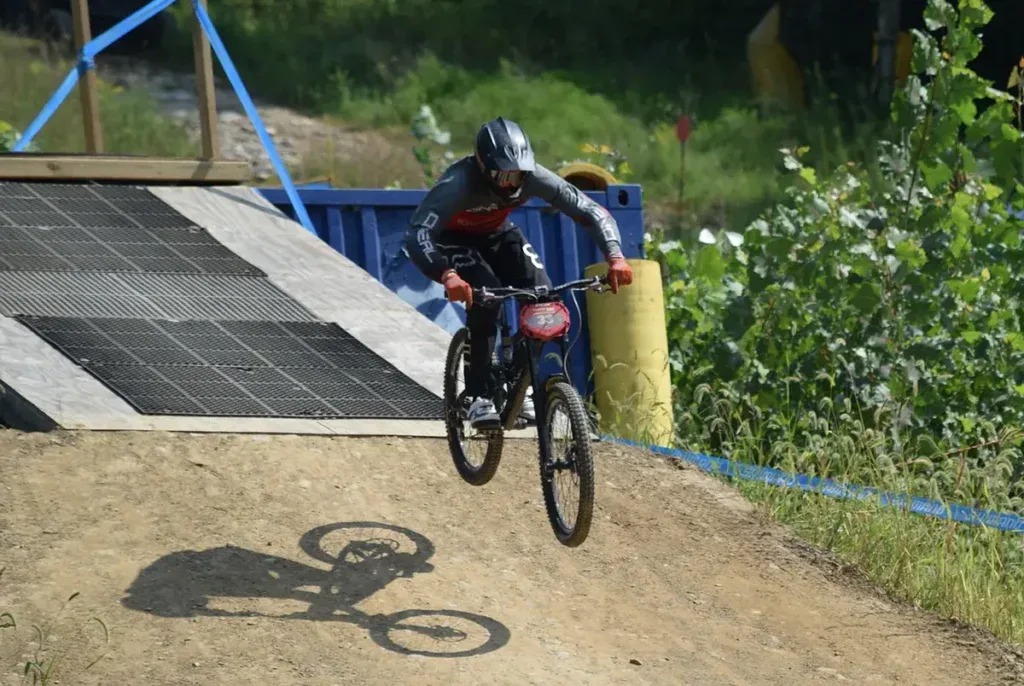 Rowerzysta w kasku w locie nad rampą na trasie bike parku